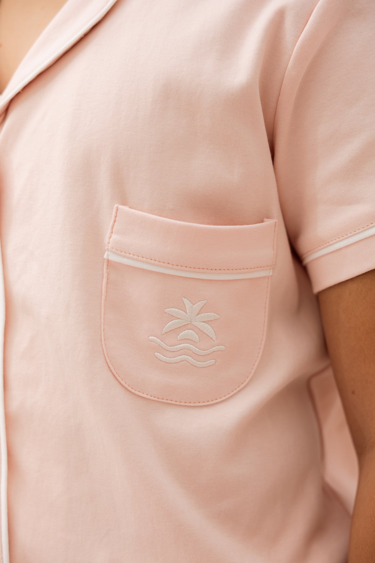 Close-up of the Neon94 Bubblegum blush pink pyjama shirt chest pocket with embroidered palm-and-wave motif