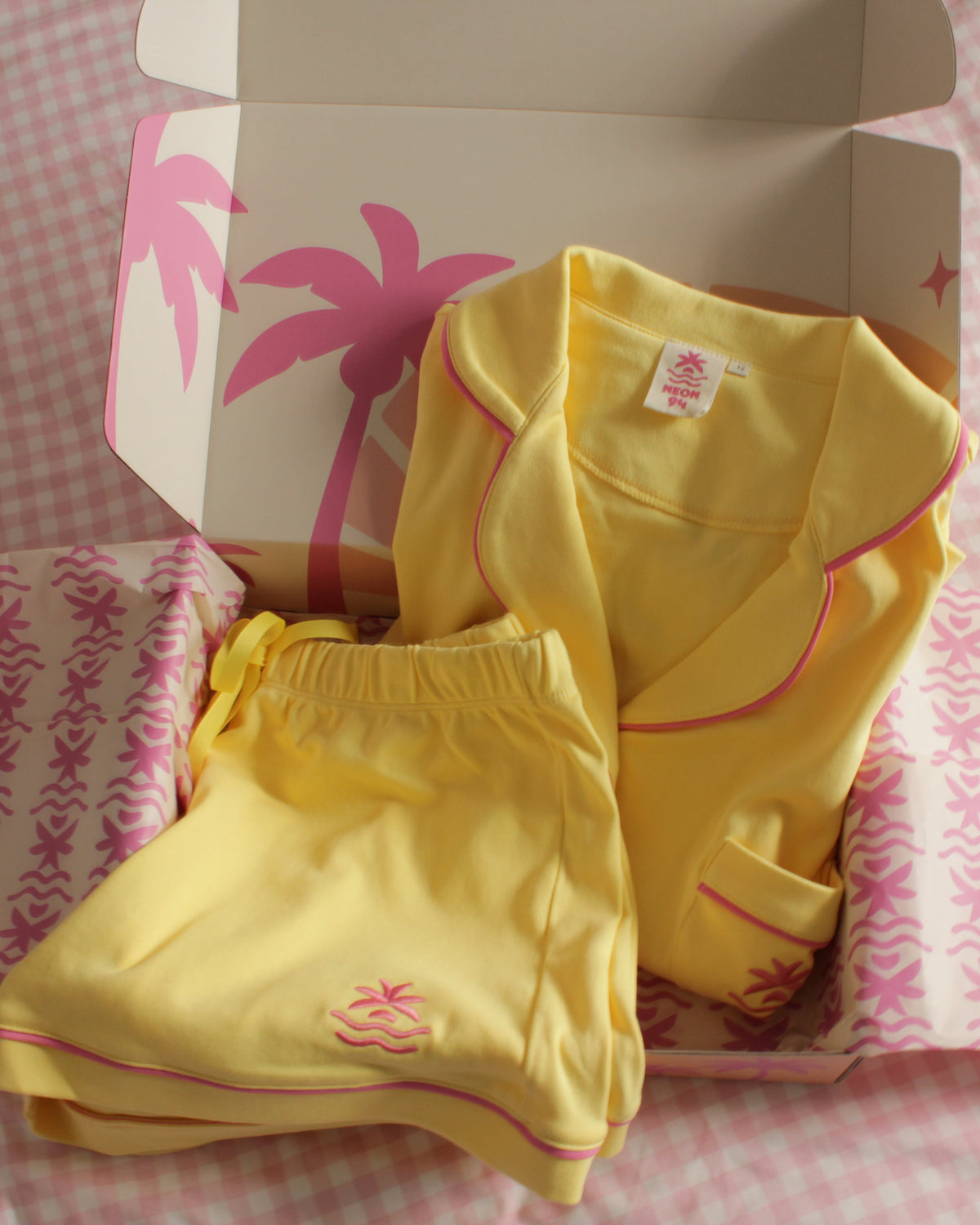 Neon94 Popcorn butter yellow Sleepover Set folded in its Neon94 gift box with palm-print tissue paper